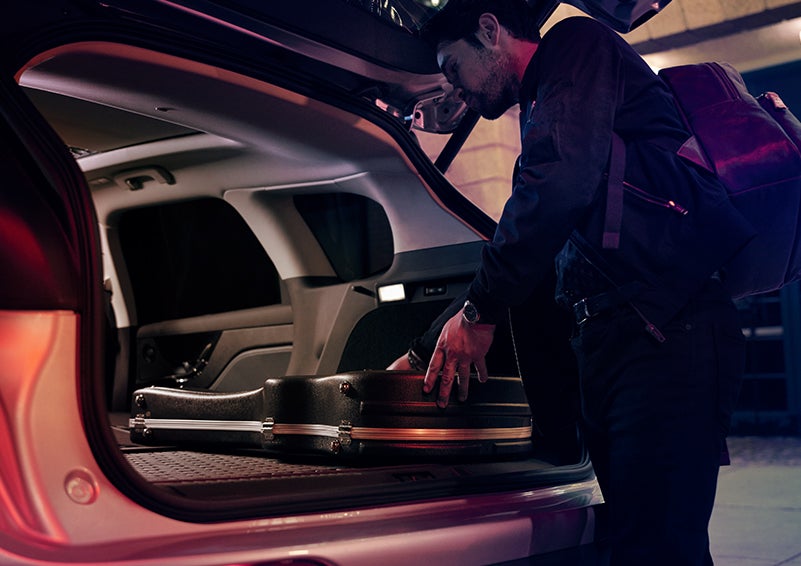 A man is shown loading cargo into the rear of a 2023 Lincoln Corsair® SUV with the second-row seats folded flat. | Star Lincoln in Southfield MI