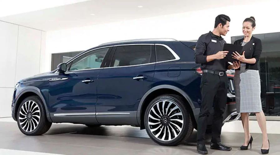 Image of a client and a Lincoln dealer in front of a blue Lincoln model.