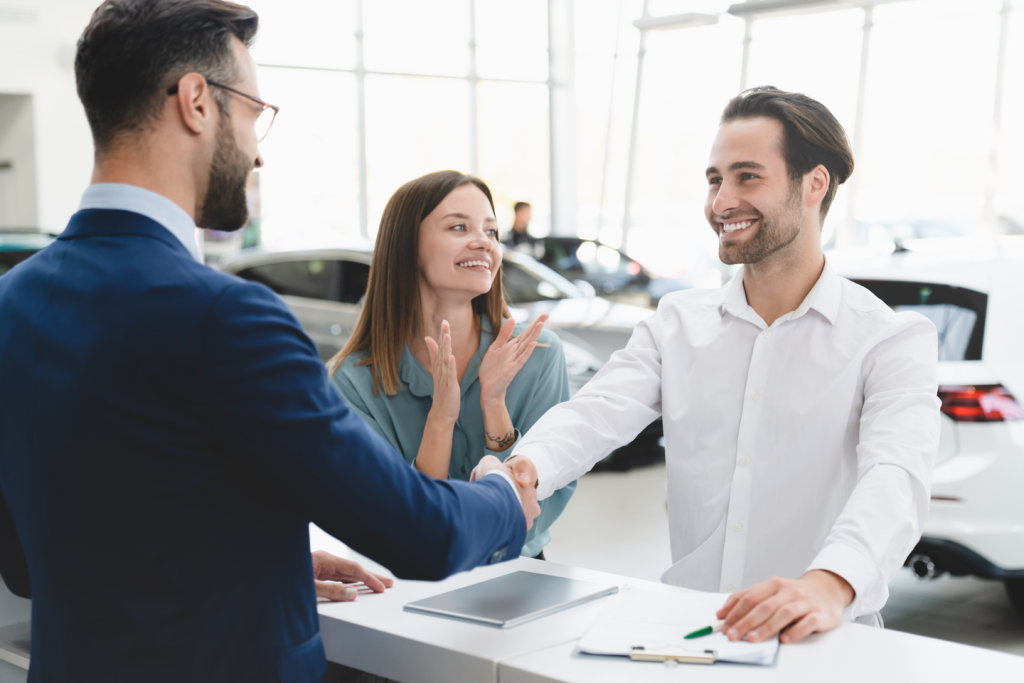 A couple signing their auto finance loan to purchase a new car happily.