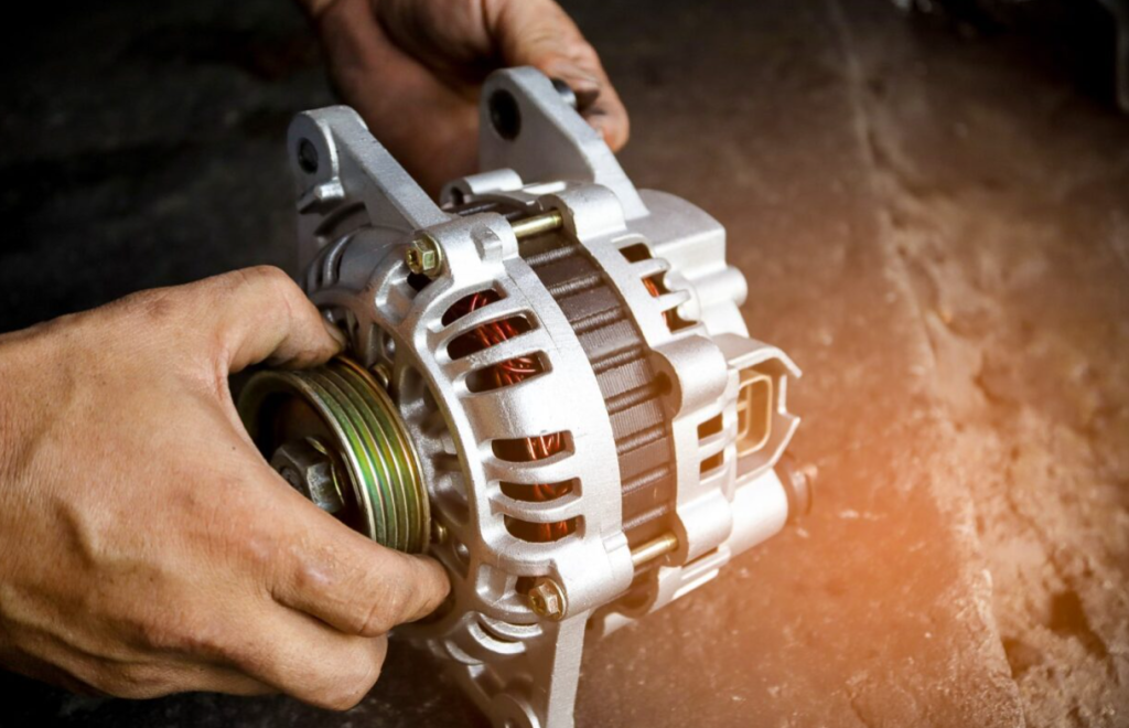 A vehicle alternator being handled by an auto repair technician.