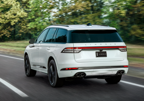 A white 2025 Lincoln Aviator® SUV is being driven away down a road lined with colorful trees. | Star Lincoln in Southfield MI