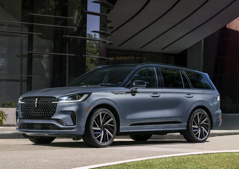A gray 2025 Lincoln Aviator® SUV is parked outside a modern building showcasing the driver’s side of the vehicle. | Star Lincoln in Southfield MI