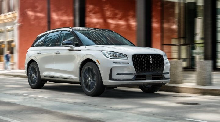 A white 2025 Lincoln Corsair® SUV with the Jet Appearance Package is being driven through a city.| Star Lincoln in Southfield MI