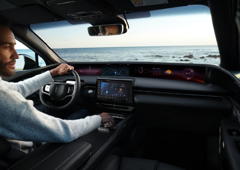 A driver of a parked 2025 Lincoln Nautilus® SUV takes a relaxing moment at a seaside overlook while inside his Nautilus. | Star Lincoln in Southfield MI