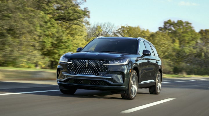 A 2026 Lincoln Black Label™ Aviator® SUV is being driven down a road lined with trees. | Star Lincoln in Southfield MI