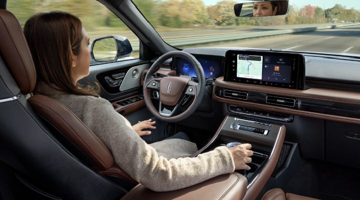 A 2027 Lincoln Aviator® SUV is being driven hands-free on a highway lined with trees. | Star Lincoln in Southfield MI