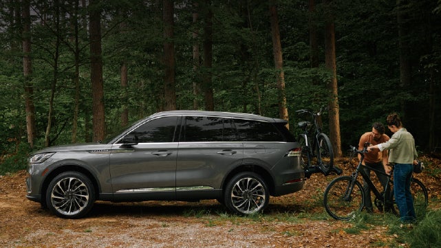 A father and son load e-bikes on a bike rack attached to a 2027 Lincoln Aviator® SUV. | Star Lincoln in Southfield MI