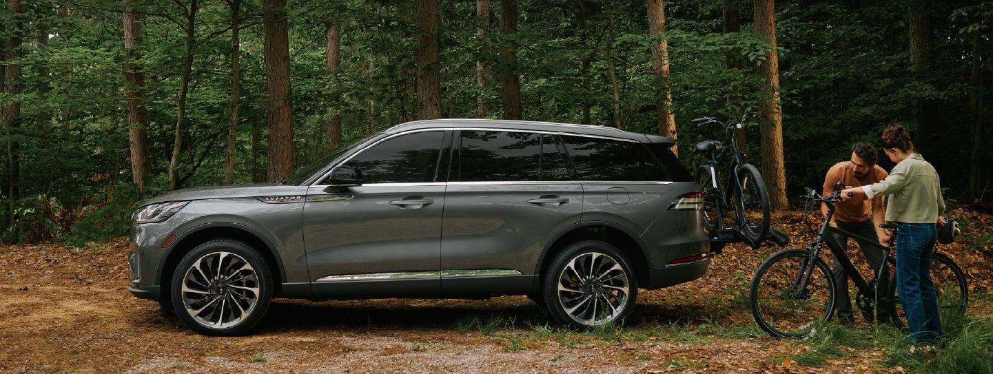 A father and son load e-bikes on a bike rack attached to a 2027 Lincoln Aviator® SUV. | Star Lincoln in Southfield MI
