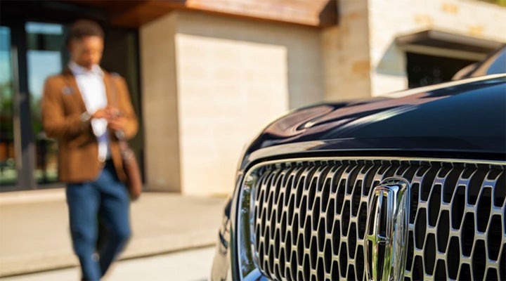 A man walking up to his Lincoln vehicle.